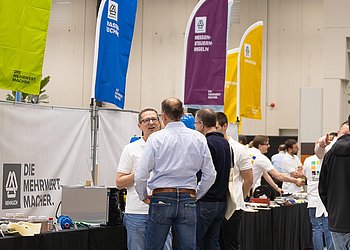Messestand mit Besuchern am Tag der Technik von HENNLICH